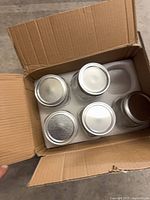 Box containing four lidded mason jars in foam