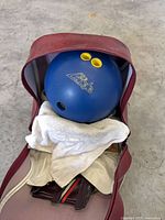 Bowling ball inside red vinyl bag, showing blue Brunswick ball with yellow finger inserts and interior towel