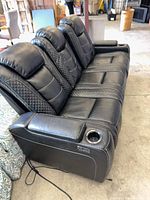 Front angled view showing three-seat sofa, quilted panels, right arm cup holder