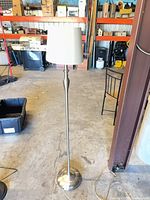 Full view of brushed nickel floor lamp standing in garage