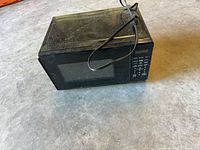 Front and top view of microwave showing overall size, black exterior, power cord