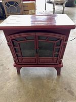 Front view of burgundy Duraflame electric fireplace stove showing twin glass doors and raised legs