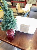 Sheet set, artificial tree and red jar on table