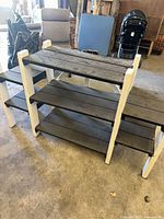 Front angled view showing three gray slat shelves and white frame