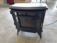 Front view of freestanding electric fireplace stove heater showing glass door and legs