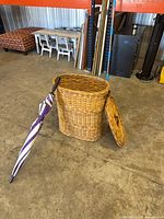 Hamper open showing interior, lid removed, umbrella leaning against hamper