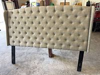Front view of tufted headboard showing upholstery and legs