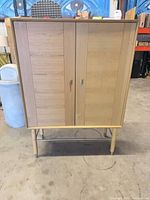 Front view of light oak veneer bar cabinet closed