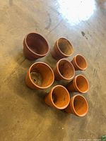 All eight terracotta pots grouped, showing exterior surfaces and variation in size