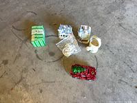 Full lot showing tin, two ceramic houses, watering-can planter, bag of cables, red car ornament