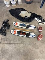 Overview of skis, skates, footballs, connector bar, wetsuit, guards on floor