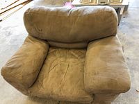 Front view of oversized taupe microfiber armchair showing overall design and wear