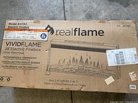 Top view of sealed Real Flame VividFlame 38" electric firebox box showing brand, model 4192 and features