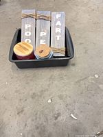 Three wooden plaques in bin with two candles visible