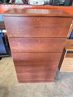 Front view of tall dresser showing five drawer fronts and veneer finish
