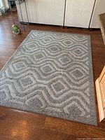 Full view of rectangular grey and off-white rug on hardwood floor