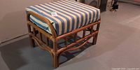 Three-quarter view of bamboo rattan footstool with striped cushion