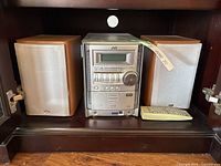 Front view of full JVC FS-G5 system showing main unit flanked by two speakers and remote