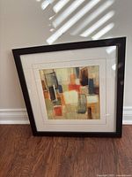 Full view of framed abstract print leaning against wall
