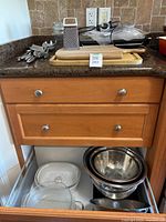 Overview of utensils on cutting board, FoodSaver behind, drawer with bowls and bakeware