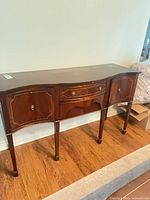 Full view of mahogany sideboard front, showing serpentine shape, drawers, cabinet doors, and legs