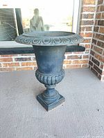 Full view of black cast iron urn planter on porch