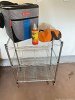 Metal wire rack with cooler bag, Pennzoil can and orange bag on top