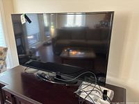Front view of 50" Samsung TV on stand with accessories visible