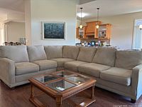 Front view of beige La-Z-Boy sectional with glass-top coffee table in foreground
