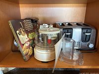 Braun food processor, Black & Decker toaster, cookbook visible on shelf