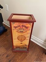 Full view of umbrella stand front with travel motif panel