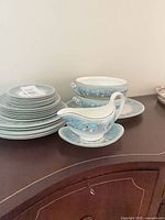 Stack of plates with gravy boat and serving dishes on sideboard