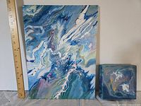 Large and small abstract paintings beside ruler for scale