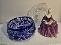 Group shot showing all three items: blue crystal bowl, crackle plate, Charlotte figurine