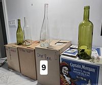 Four loose bottles on top of two boxed cases; boxes labelled indicating bottle styles