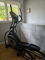 Front side view of Regent elliptical positioned by window and dresser