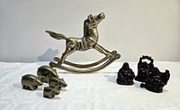 Group shot showing brass rocking horse, four brass pigs, three resin Buddhas