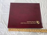 Closed maroon binder with gold title next to ruler