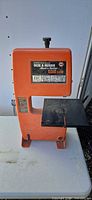 Front view of orange Black & Decker drill-powered benchtop band saw showing table and base