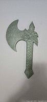 Front view of pale green carved stone axe with dragon relief and curved blade