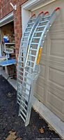 Pair of folded galvanized steel loading ramps leaning against garage door