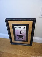 Full view of framed signed Hamilton Playbill resting against wall