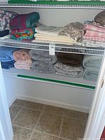 Two shelves of folded towels and sheets in closet