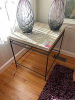 End table by window with wood veneer top and metal frame