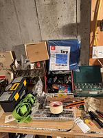 Workbench with packaged blue tarp, green socket set, hardware organisers, toolbox, straps, tape