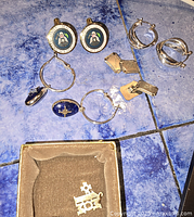 Overview of jewelry pieces on blue tile including presidential cufflinks, sterling cufflinks, earrings, rings, studs and lapel pin