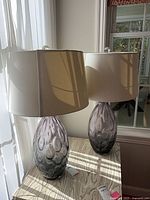 Both purple glass lamps with shades on table
