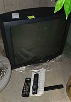 Front view of Panasonic CRT TV with two remotes on floor