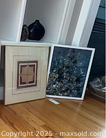 Both framed prints leaning against wall