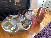 All four pieces grouped: iridescent glass bowl, porcelain floral vase, pink glass vase, copper-tone vase
